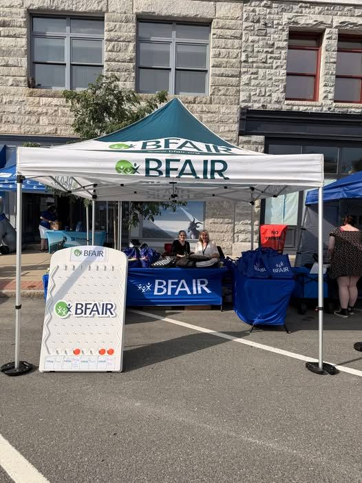 A pop up tent with BFAIR staff handing out school supplies