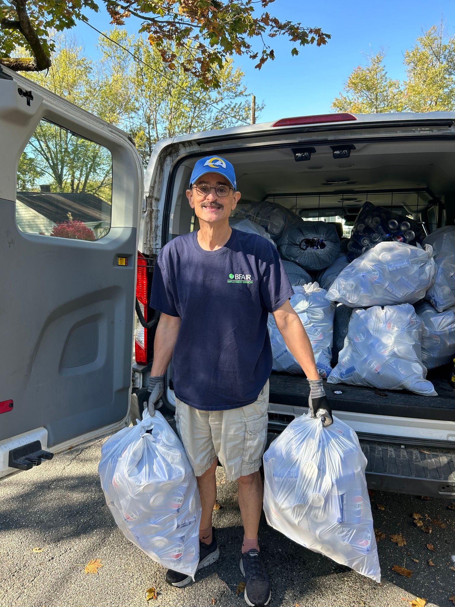 An individual who works in BFAIR's employment program holding bags of recycled cans