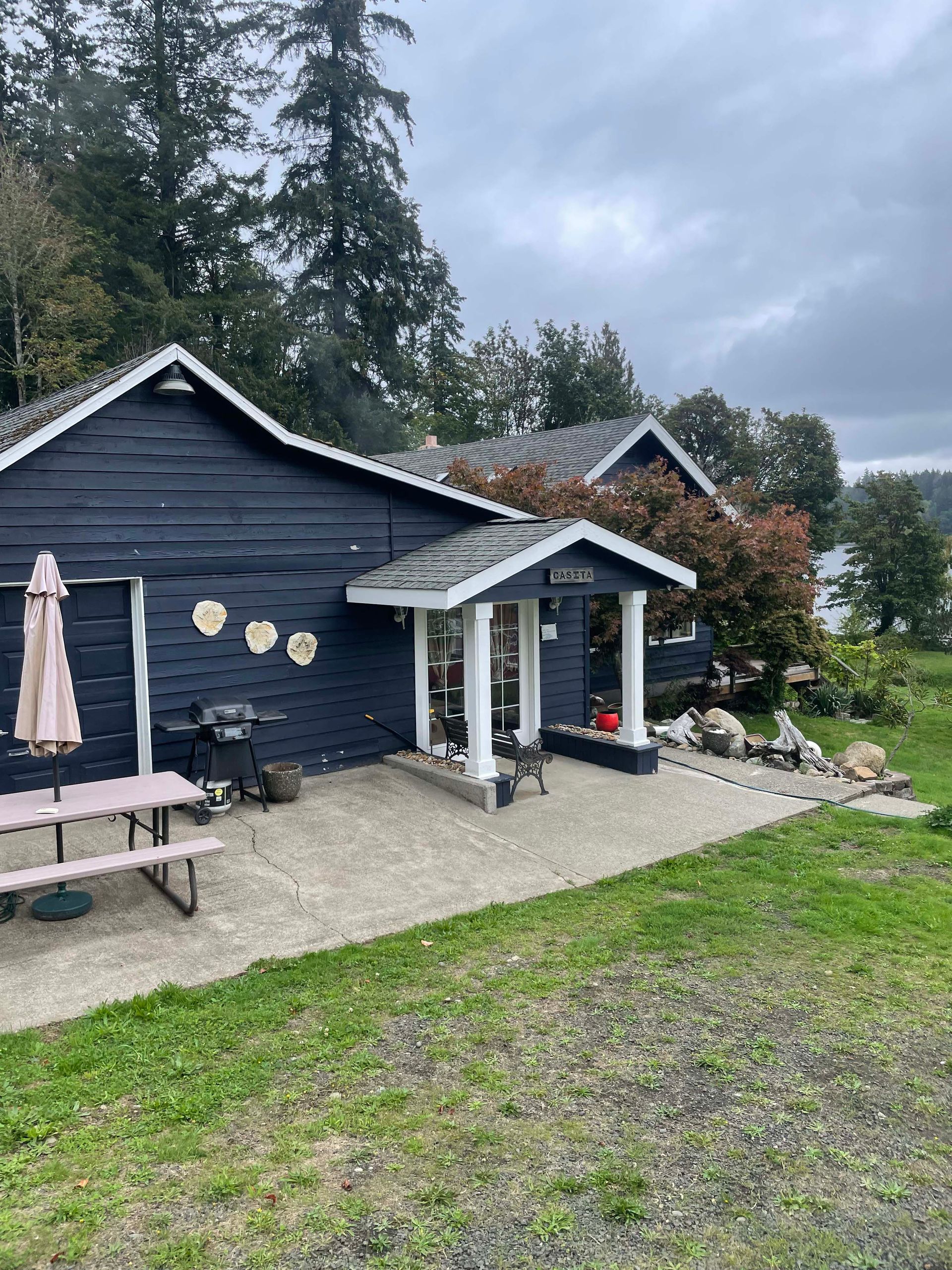 A black house with a picnic table and umbrella in front of it