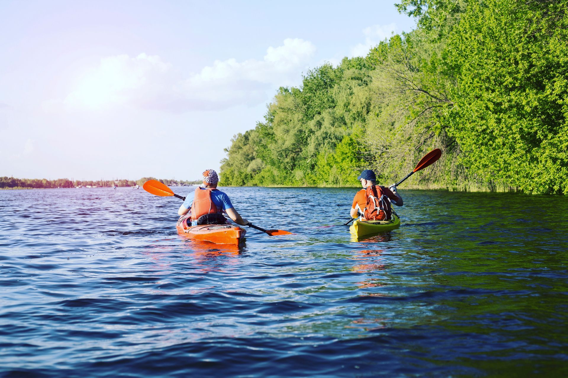 Two people are paddling kayaks on a lake.