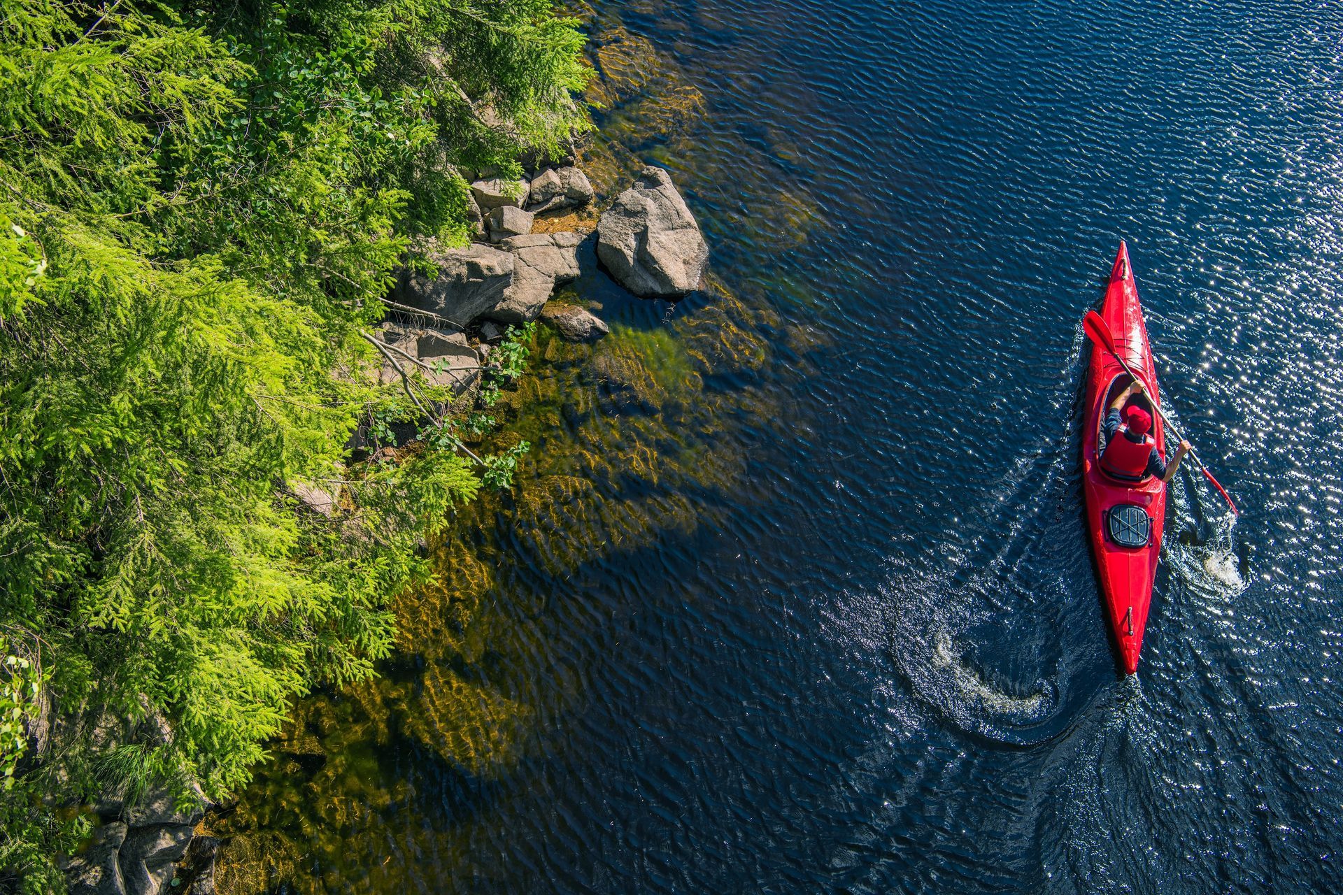 An aerial view of a person in a red kayak on a lake.