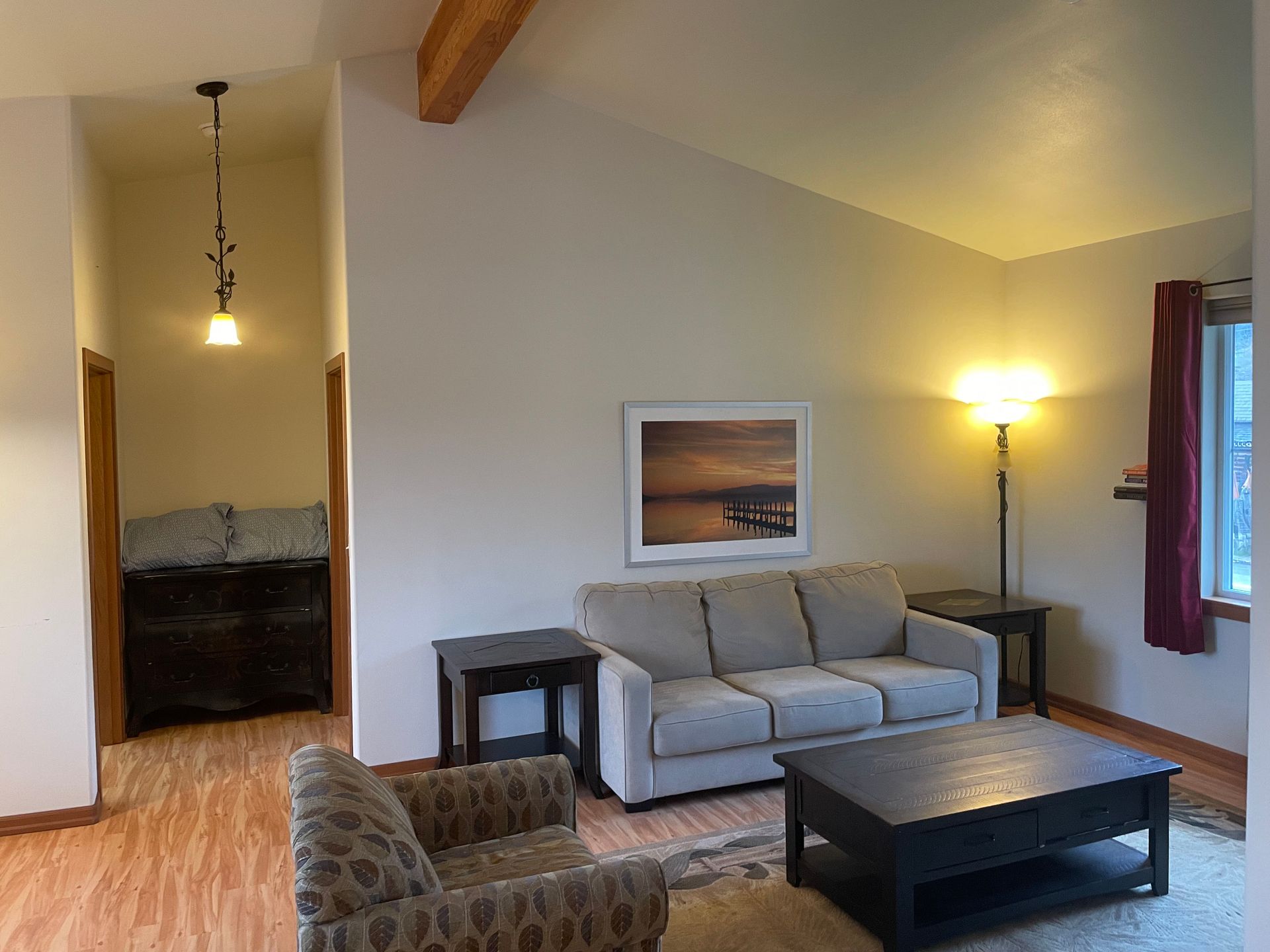 A living room with a couch , chair , coffee table and picture on the wall.