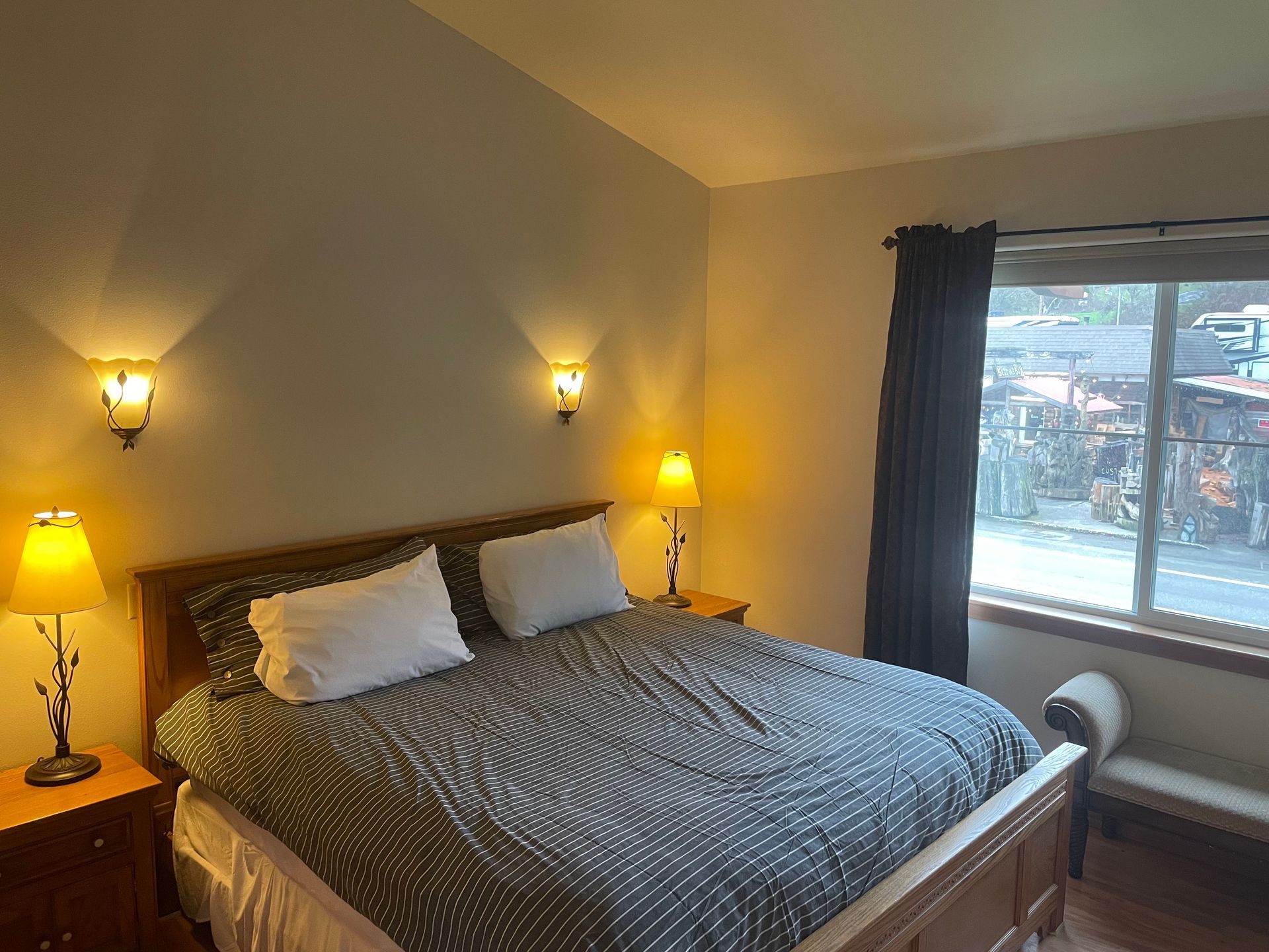 A bedroom with a large bed , two lamps and a window.