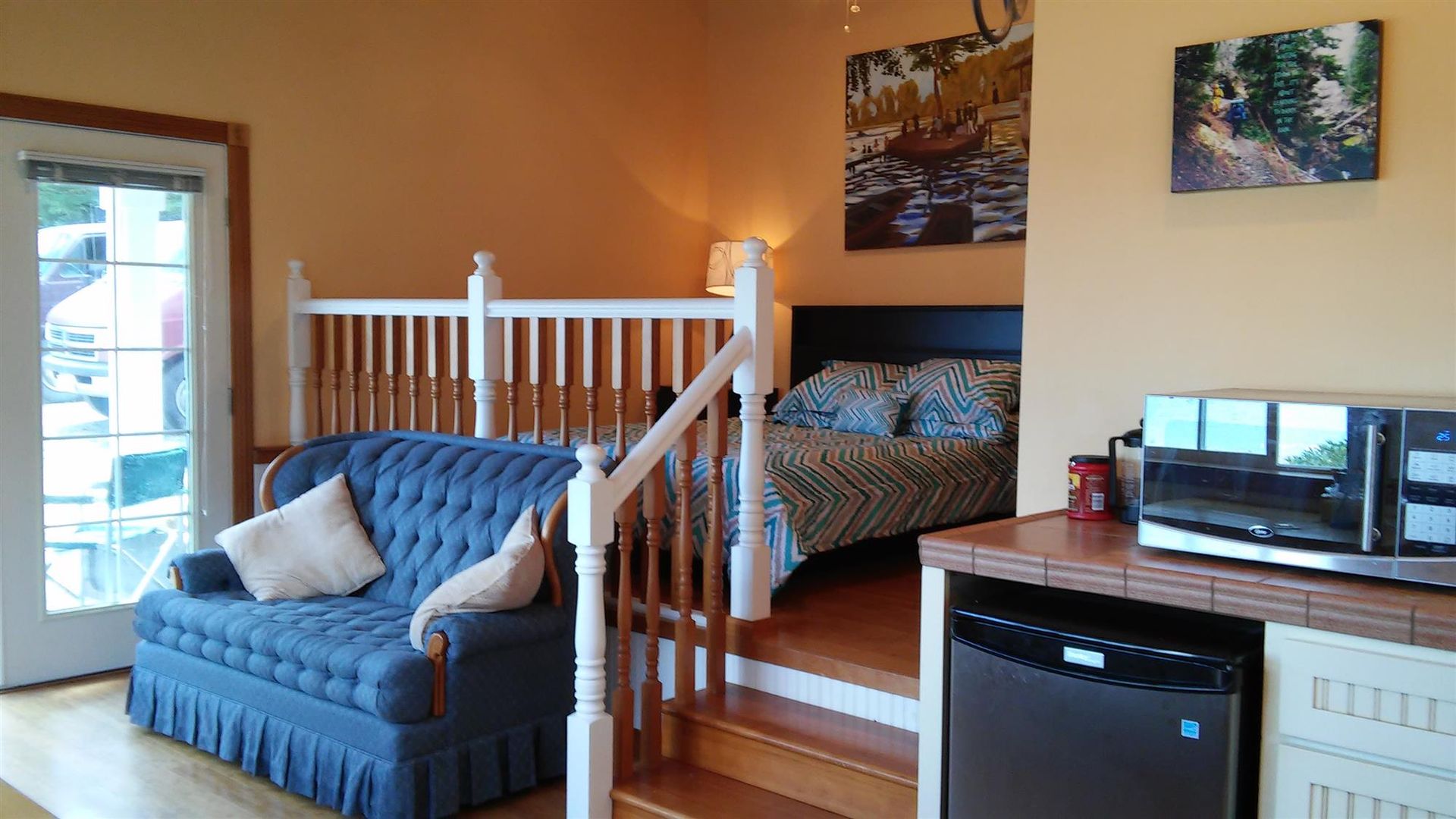 A living room with a couch and stairs leading to a bedroom.