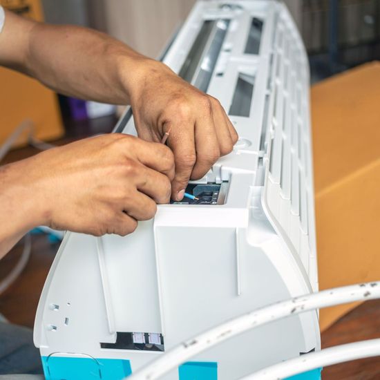 Davis Appliance & Tool Repair - a man is fixing an air conditioner with his hands.