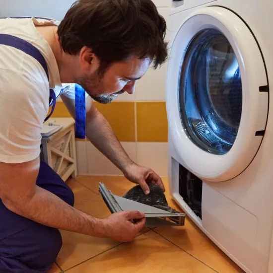 Davis Appliance & Tool Repair - A man is working on a washing machine in a bathroom