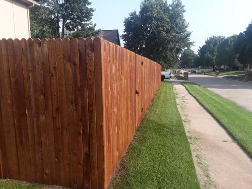 A wooden fence along a sidewalk in a residential neighborhood.