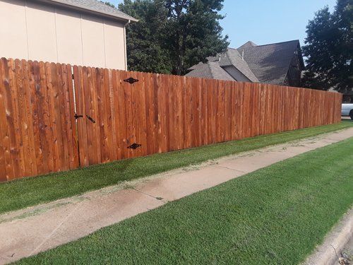 A wooden fence along a sidewalk next to a house.