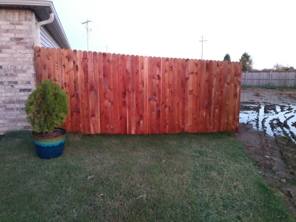 A wooden fence is in the backyard of a house.