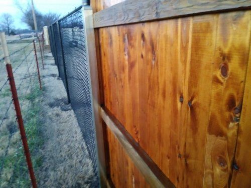 A close up of a wooden fence next to a chain link fence.