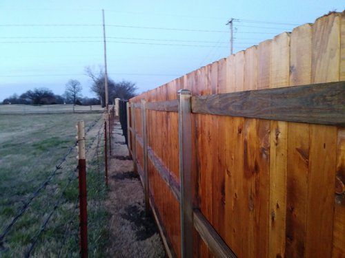 A wooden fence surrounds a field with power lines in the background.