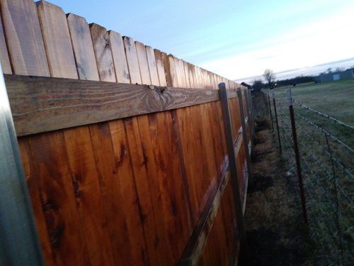 A wooden fence is surrounded by a wire fence in a field.