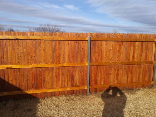 A wooden fence with a shadow of a person standing in front of it.