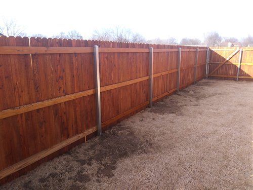 A wooden fence is sitting in the middle of a dirt yard.