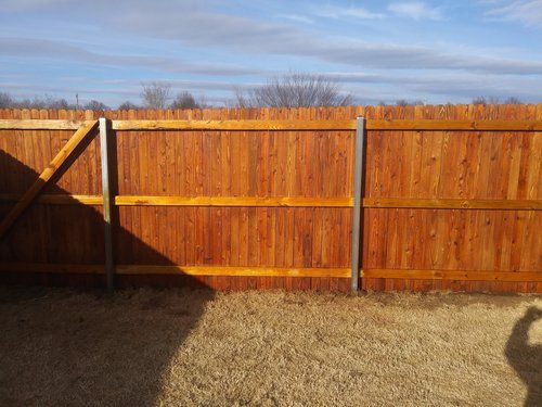 A wooden fence is sitting in the middle of a gravel yard.