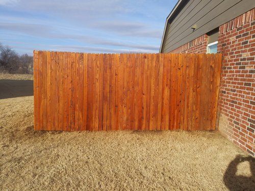 A wooden fence is sitting in front of a brick building.