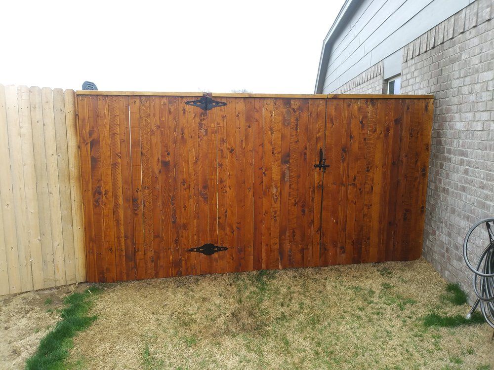 A wooden fence is in the backyard next to a brick wall.