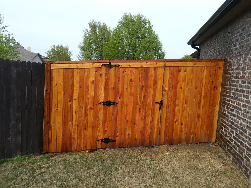 A wooden fence is sitting next to a brick wall.