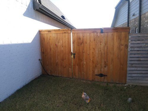 A wooden fence is in the backyard of a house.