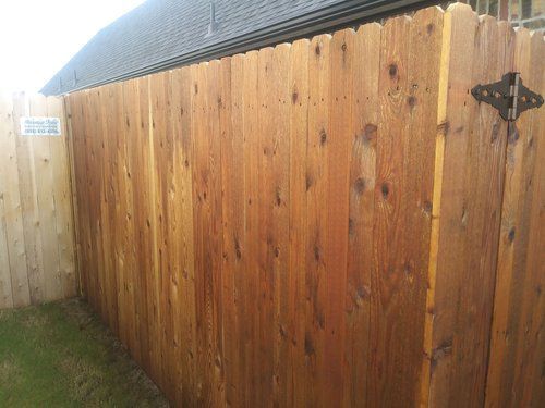 A wooden fence with a gate in the backyard of a house.