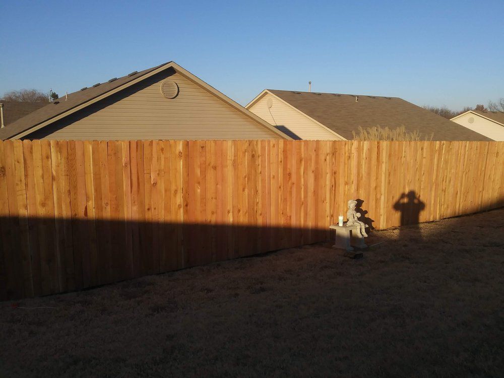 A shadow of a person is cast on a wooden fence