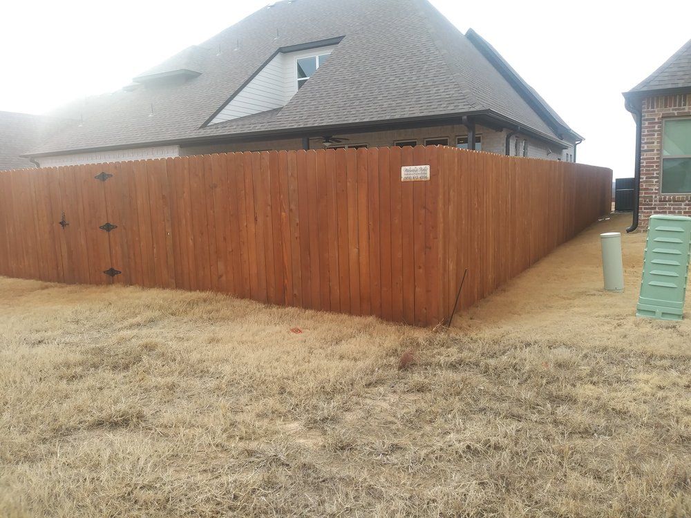 A wooden fence is in the backyard of a house.