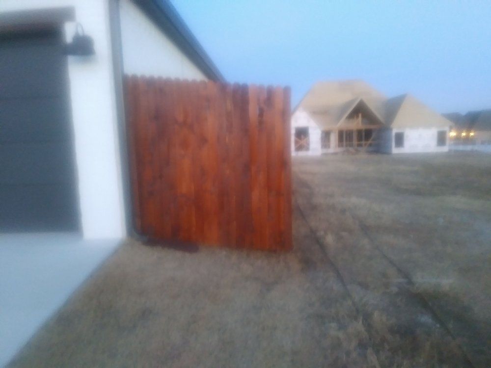 A wooden fence in front of a house under construction