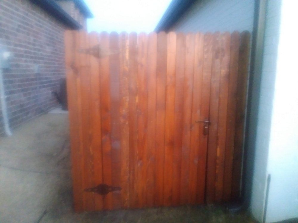 A wooden fence with a door in the backyard of a house.