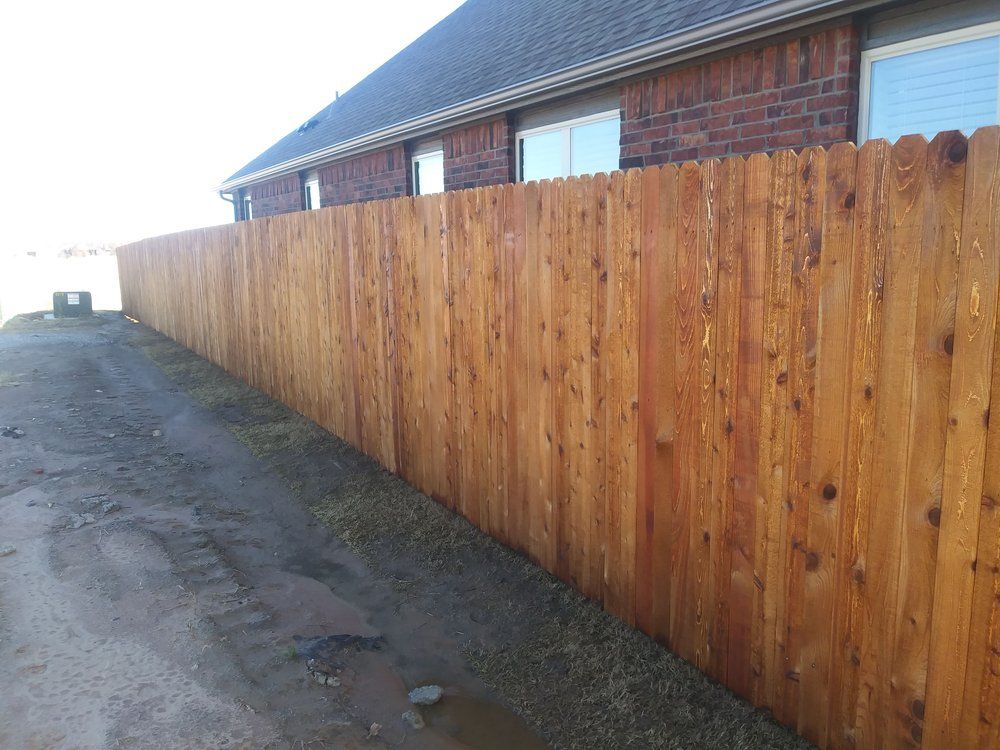 A wooden fence is in front of a brick building.