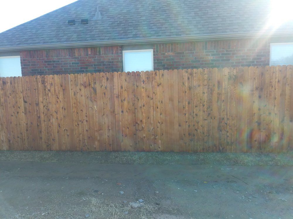 A wooden fence is in front of a brick house.