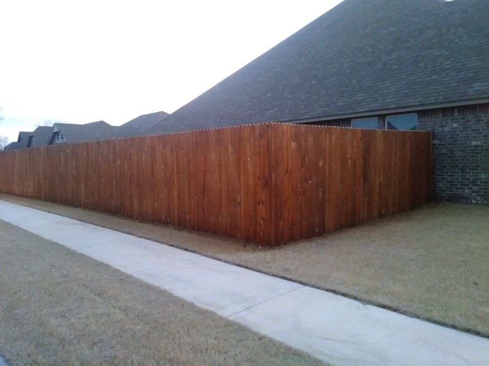 A wooden fence along a sidewalk in front of a house.