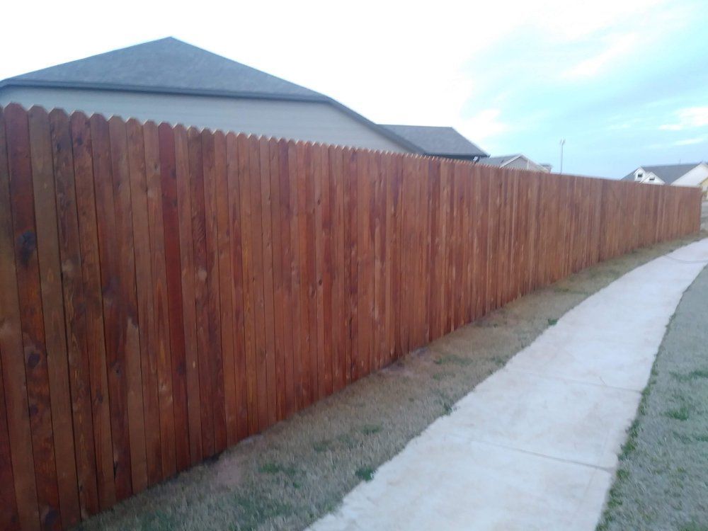 A wooden fence along a sidewalk next to a house.
