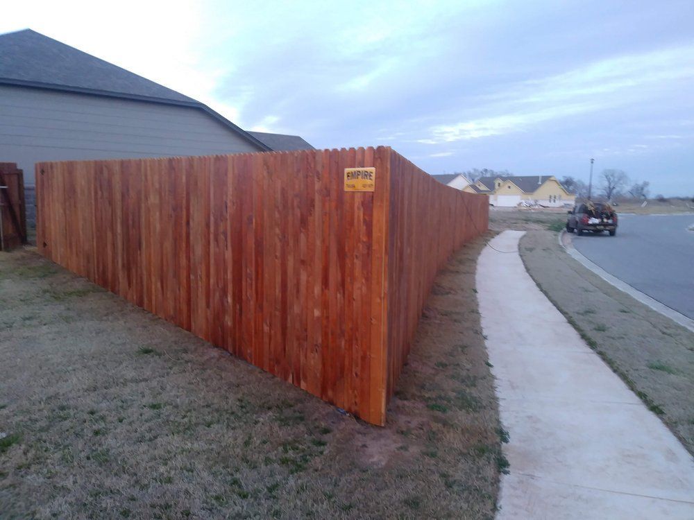 A wooden fence along a sidewalk next to a house