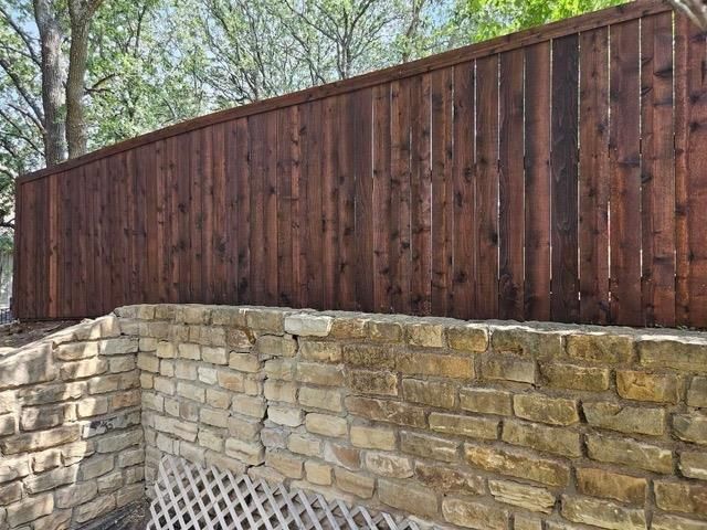 A wooden fence is sitting on top of a stone wall.