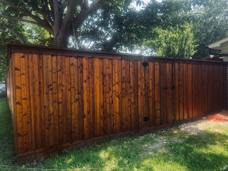 A wooden fence is sitting in the grass in front of a house.