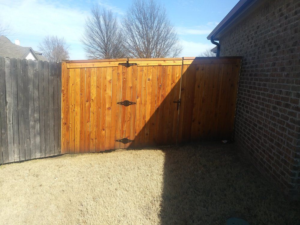 A wooden fence with a brick wall behind it