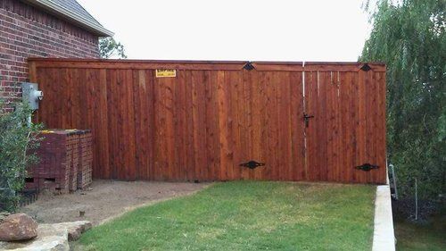 A wooden fence is in the backyard of a house.