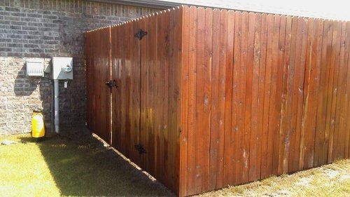 A wooden fence is sitting in front of a brick building.
