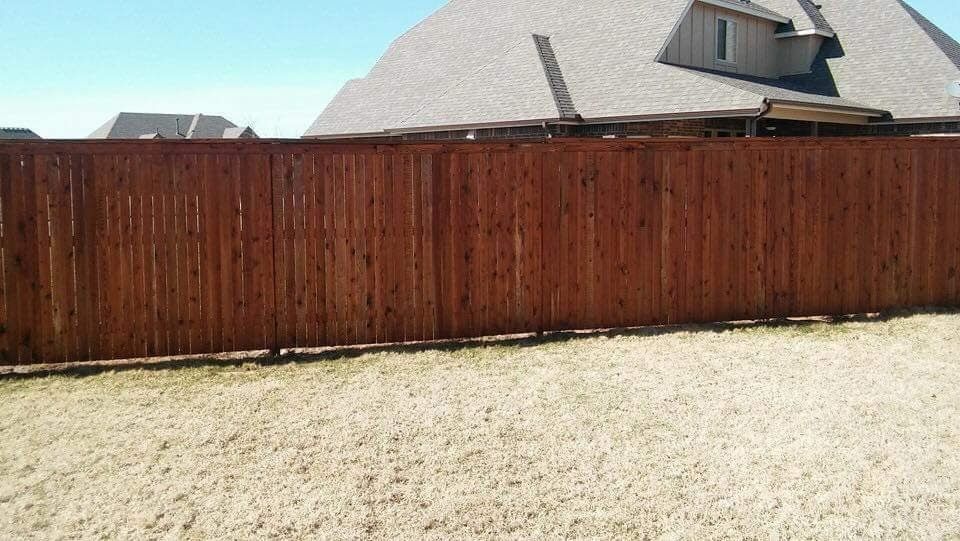 There is a wooden fence in the backyard of a house.