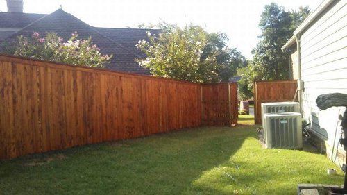 A wooden fence is in the backyard of a house.