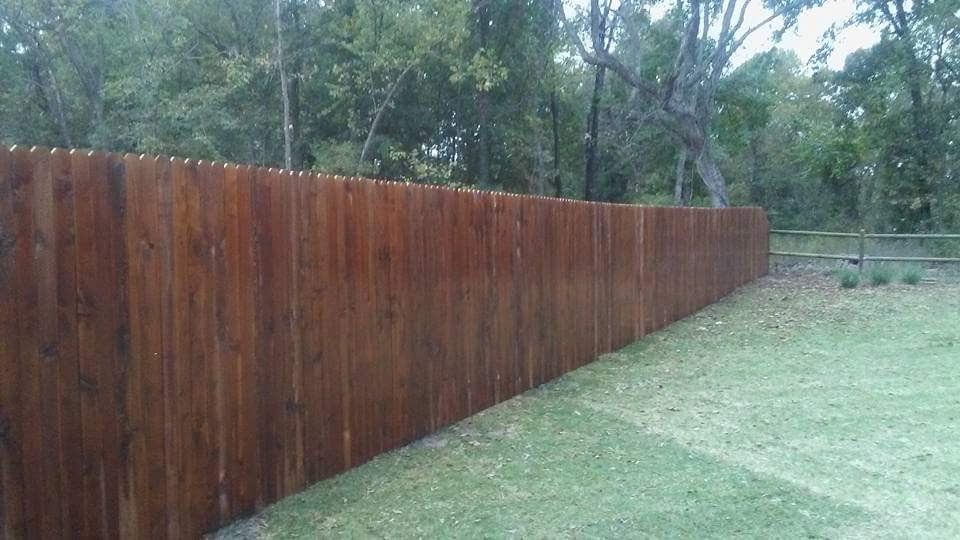 A wooden fence is sitting in the middle of a lush green field.