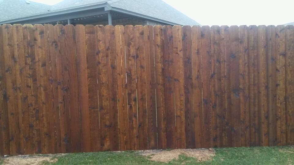 A wooden fence is sitting in the grass in front of a house.
