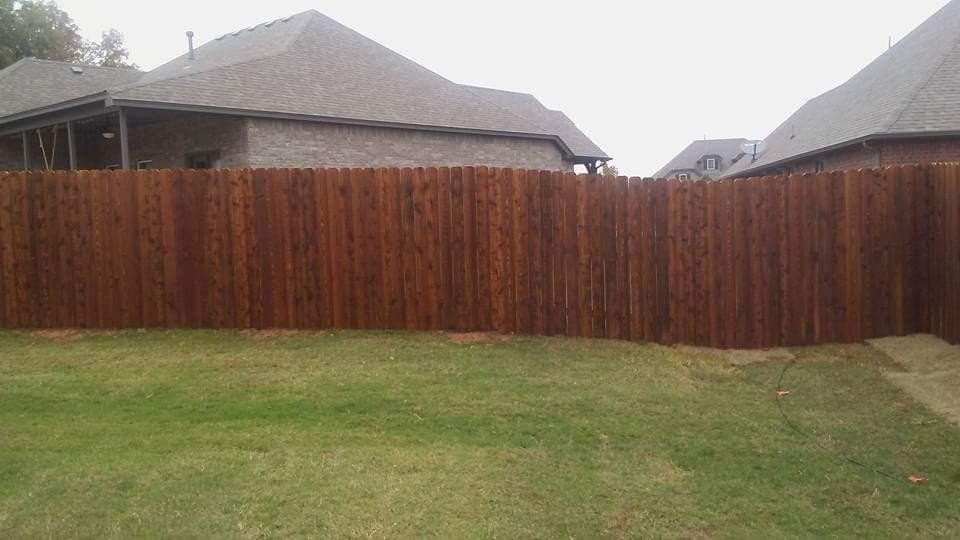 A wooden fence is in the backyard of a house.
