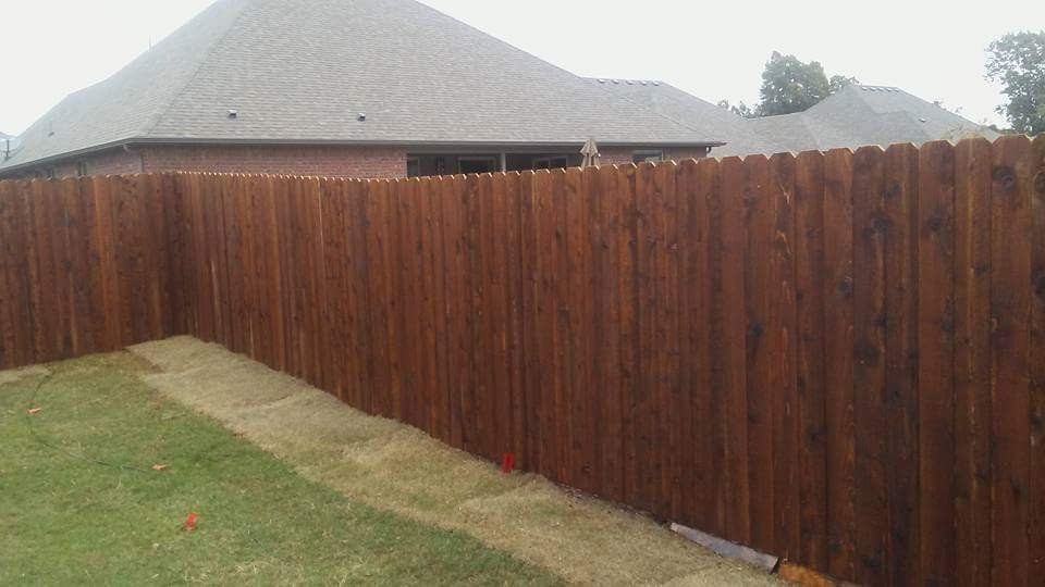 A wooden fence is in the backyard of a house.