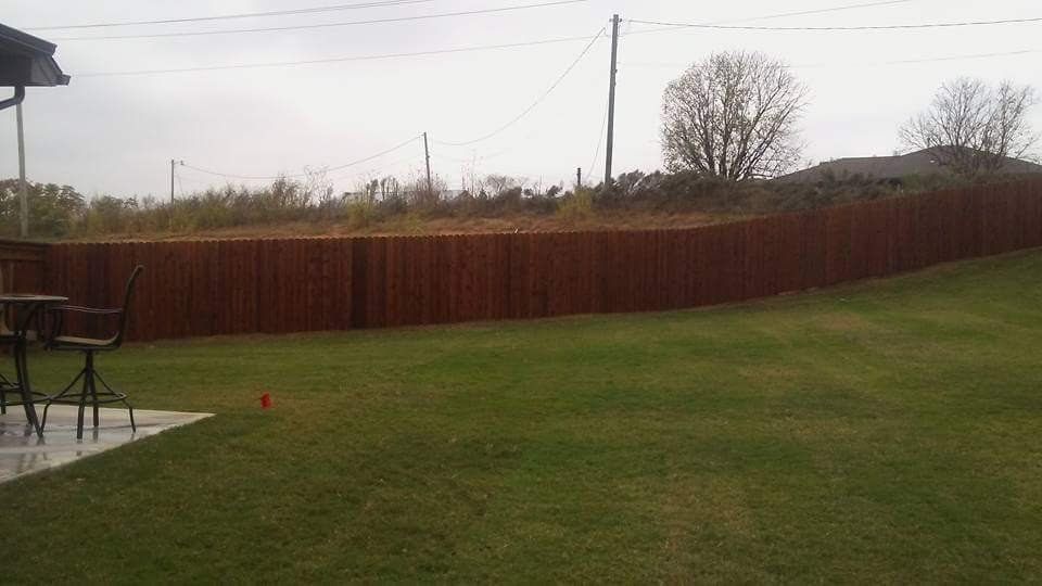 A backyard with a wooden fence and a table and chairs.