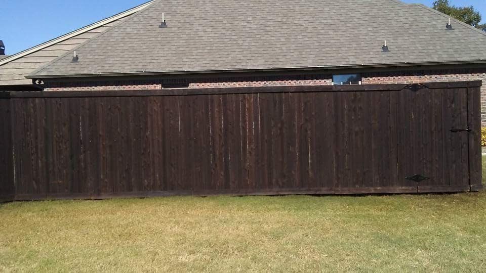 A wooden fence is sitting in the grass in front of a house.