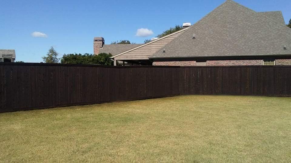 There is a wooden fence in the backyard of a house.