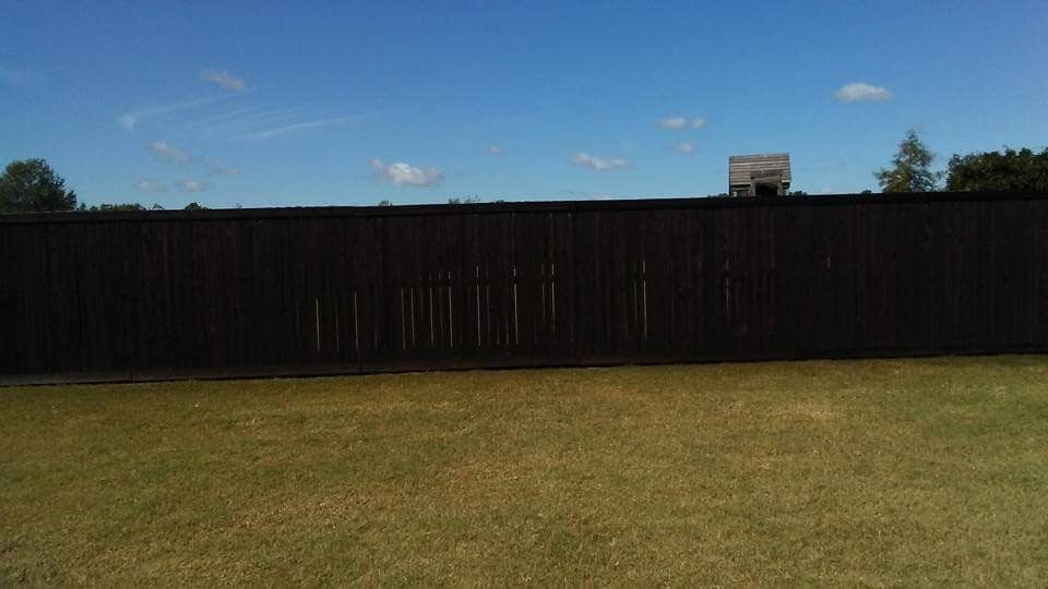 A wooden fence surrounds a grassy field with a blue sky in the background.