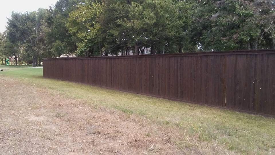 A long brown wooden fence surrounds a grassy field.