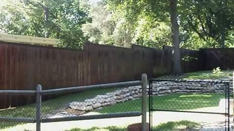 A wooden fence with a chain link fence and a gate in a yard.